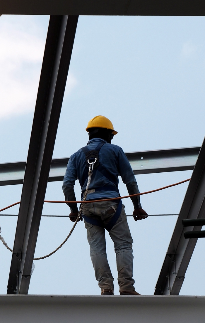 A construction worker in a safety harness on a highrise frame
