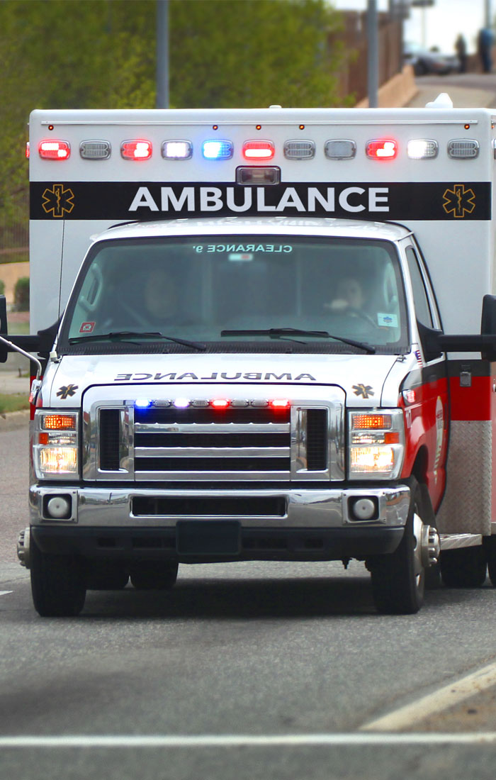 An ambulance with its lights on driving down a street